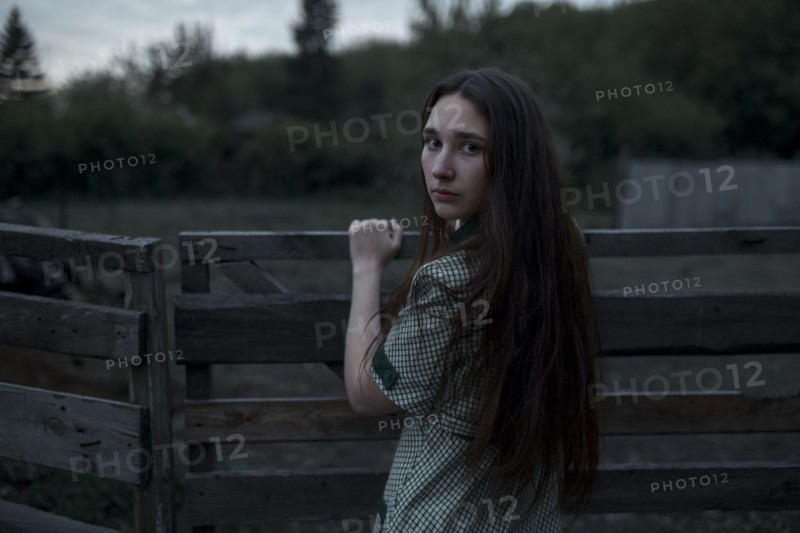 Caucasian woman leaning on wooden gate