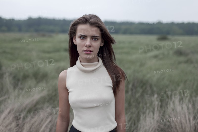 Serious Caucasian teenage girl standing in field