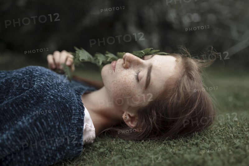Caucasian girl with freckles laying in grass