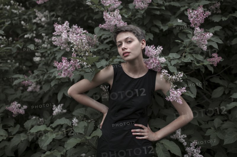 Caucasian woman near flowering tree with hands on hips