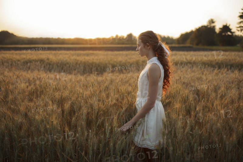 Pensive Caucasian girl standing in field of wheat