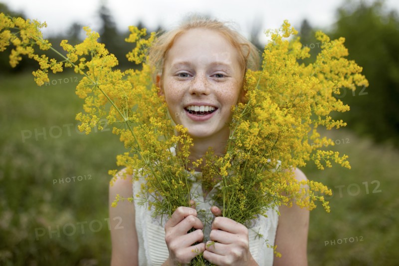 Portrait of smiling Caucasian girl with freckles holding wildflowers