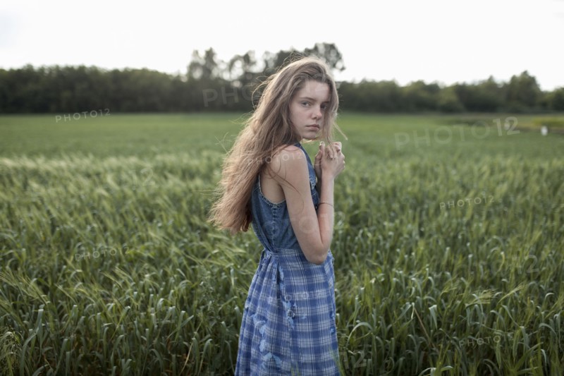 Wind blowing hair of serious Caucasian woman in field