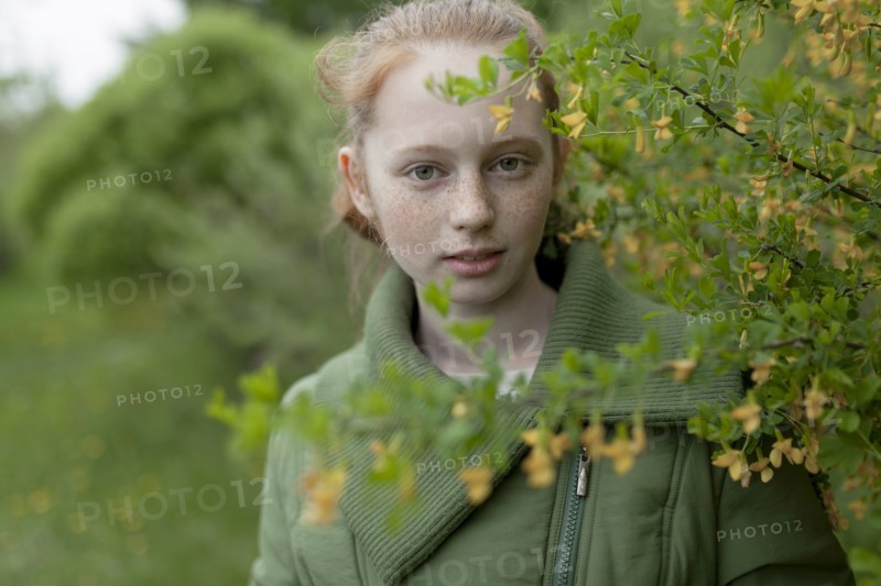 Close up of Caucasian girl standing near branch