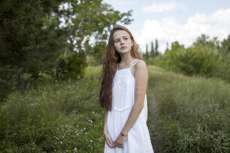 Pensive Caucasian girl standing in field