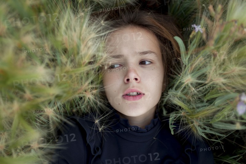 Concerned Caucasian girl laying in field