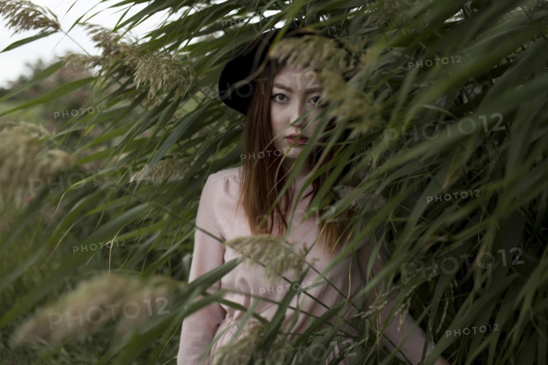 Portrait of serious Asian woman standing in field of tall grass