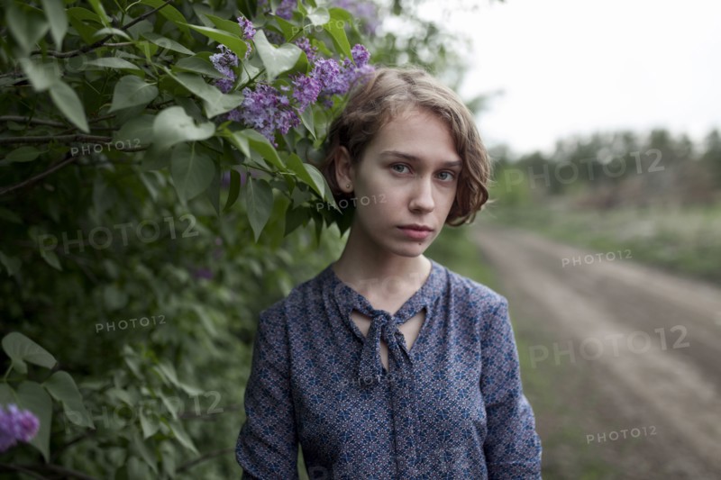 Pensive Caucasian woman standing near flowers