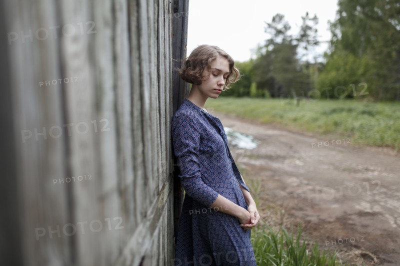 Pensive Caucasian woman leaning on wooden fence