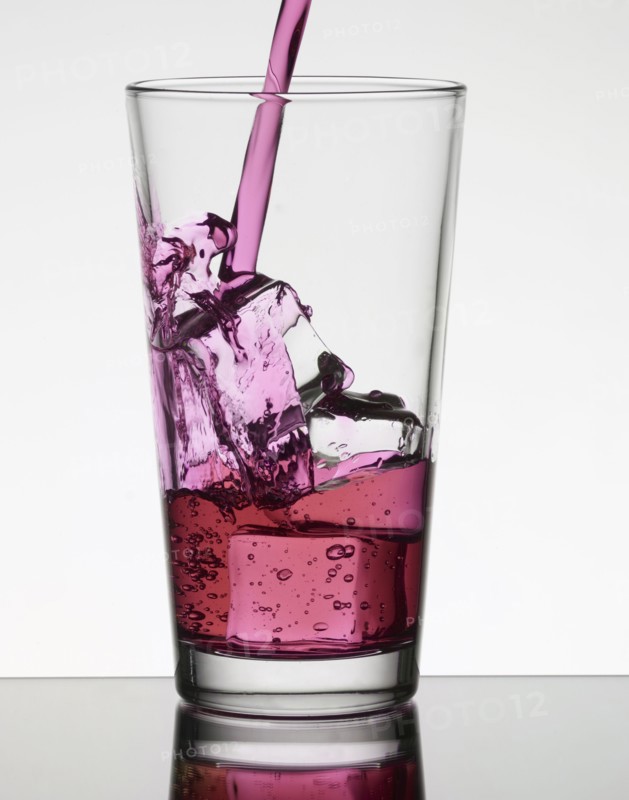 Pink liquid filling glass with ice