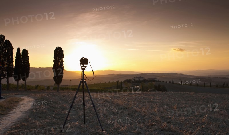 Camera in field on tripod at sunset