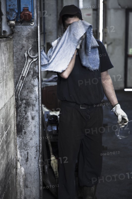 Caucasian worker wiping his face in factory