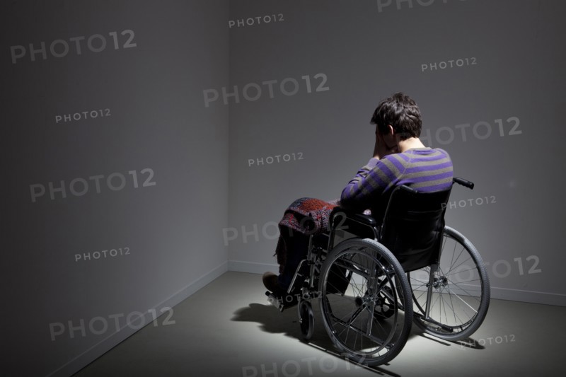 Frustrated Caucasian man in wheelchair in corner