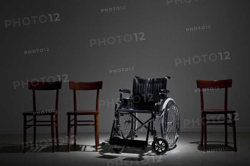 Wheelchair in line of wooden chairs