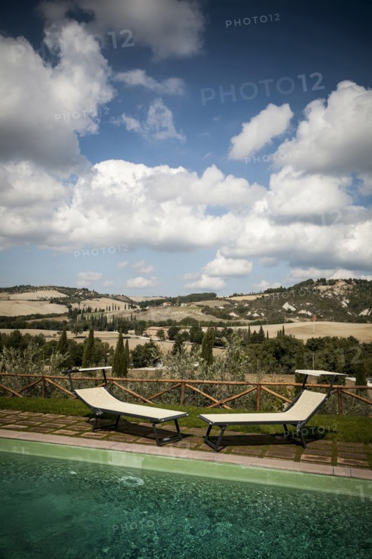 Lawn chairs by pool in rural landscape