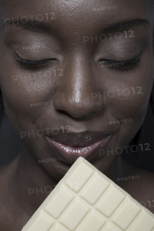 Close up of black woman eating bar of white chocolate