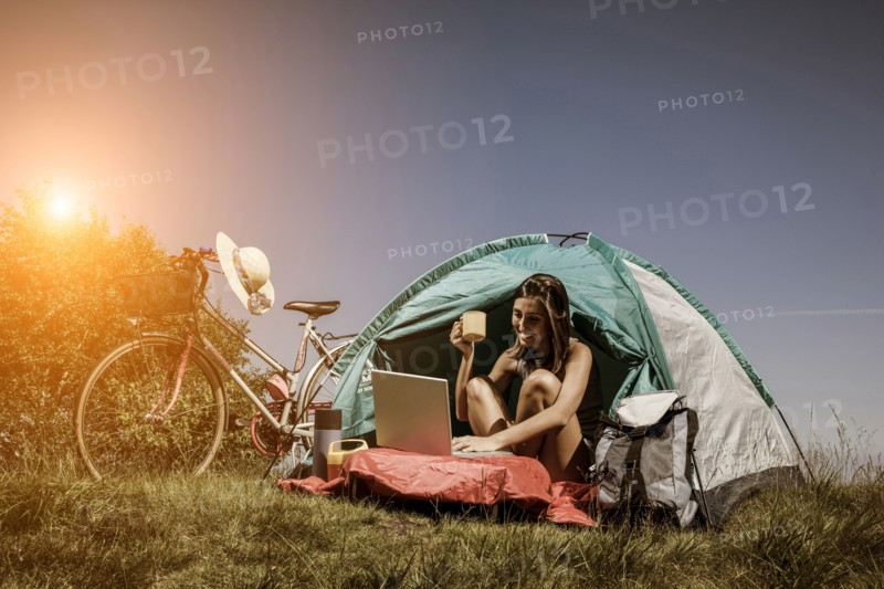 Woman using laptop in camping tent