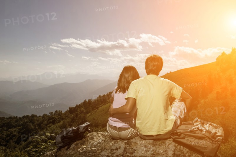 Couple sitting on rock admiring scenic view of mountain