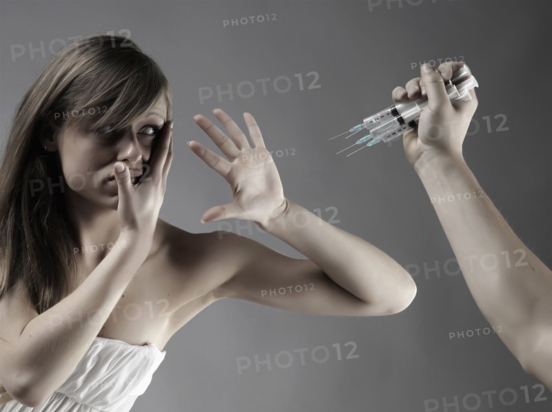 Caucasian woman protecting face from syringes