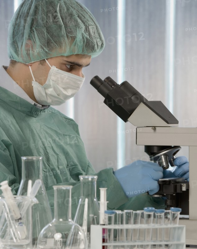Caucasian scientist using microscope in laboratory