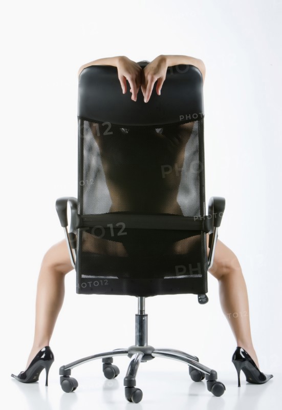 Naked Caucasian woman wearing high heels in office chair