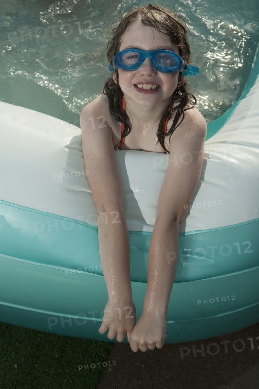 Smiling Caucasian girl in inflatable swimming pool