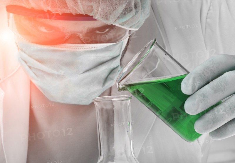 Caucasian scientist pouring green liquid into beaker