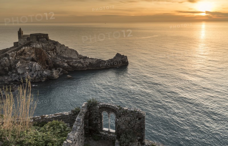Stone building near ocean at sunset