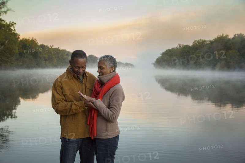 Older couple looking at ring at foggy river at sunrise