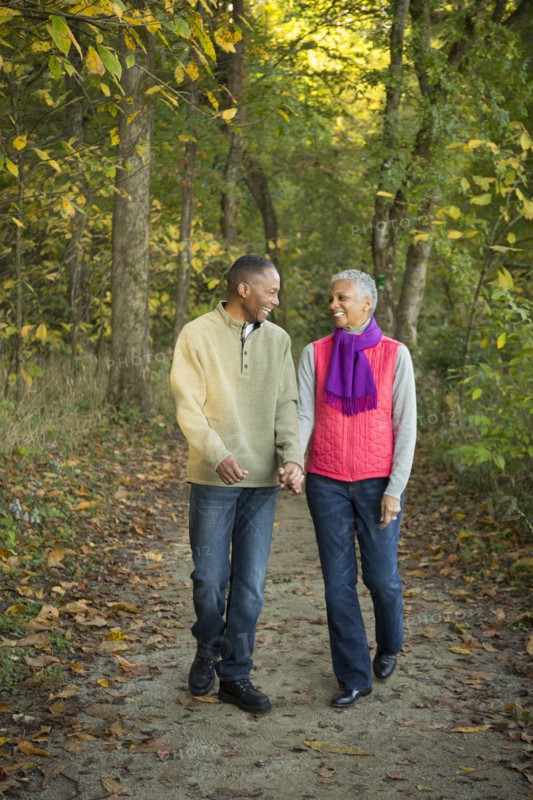 Older couple holding hands walking in forest