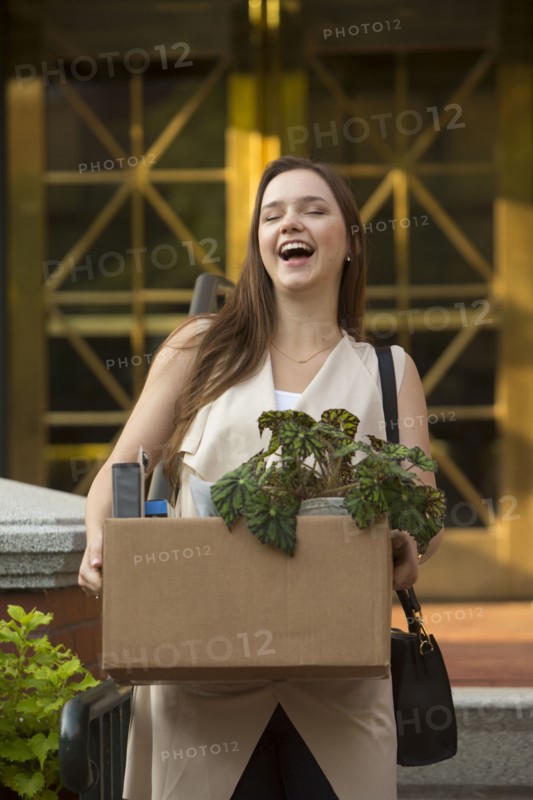Laughing Caucasian carrying box with potted plant