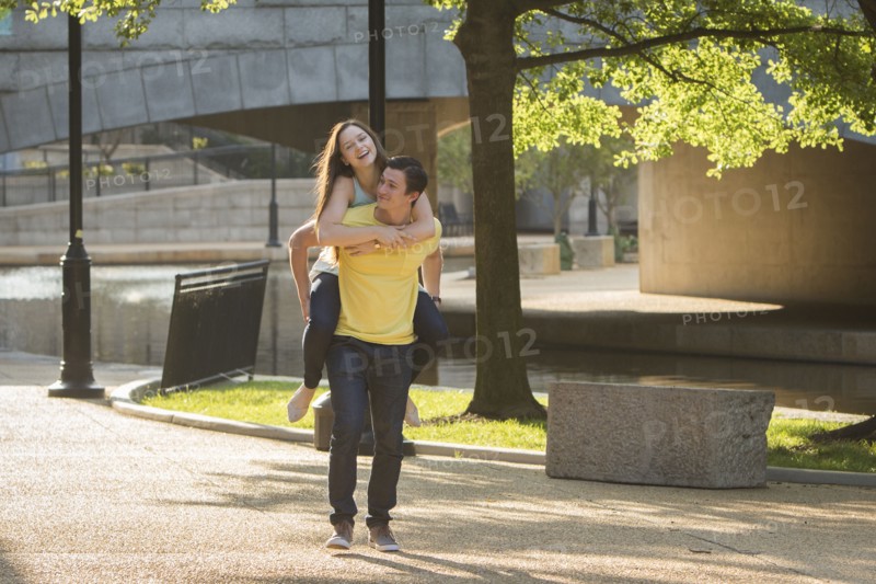 Caucasian man carrying girlfriend piggyback in park