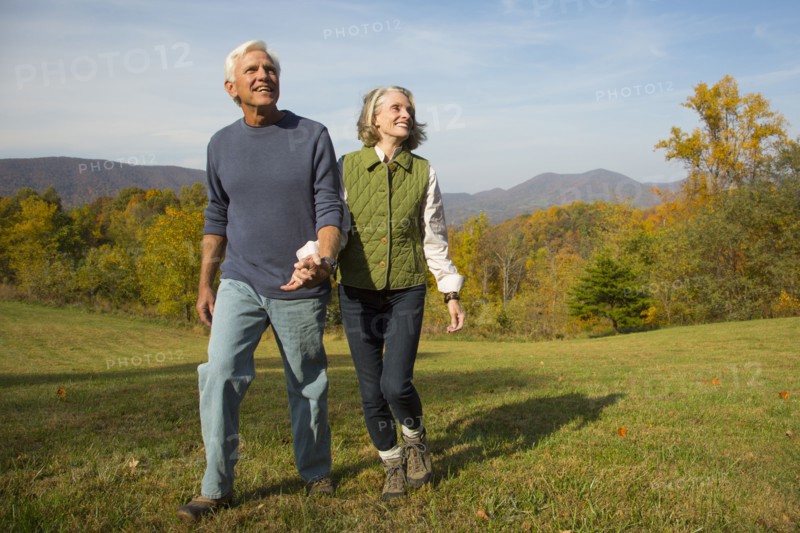 Older Caucasian couple walking in field