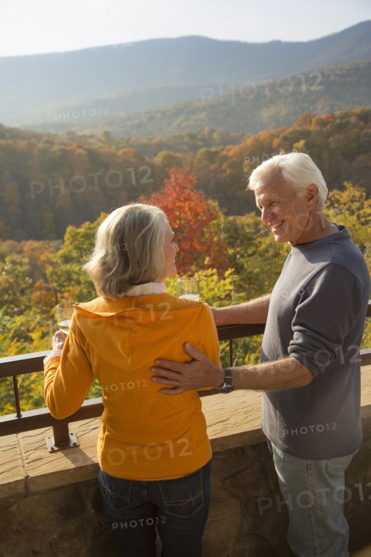 Older Caucasian couple enjoying wine and scenic view