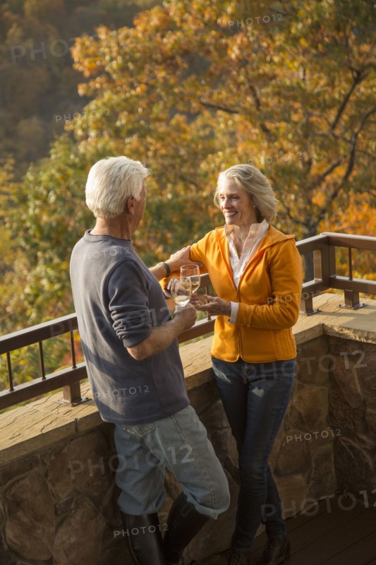Older Caucasian couple enjoying wine and scenic view