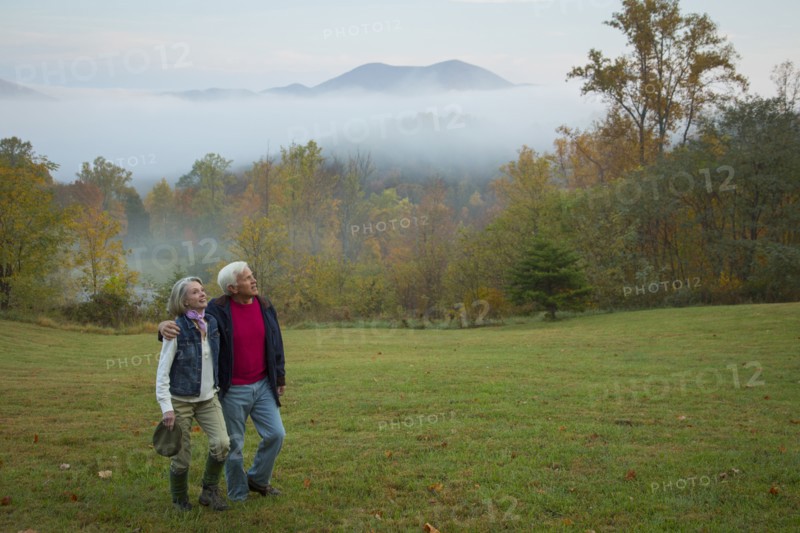Older Caucasian couple walking in field
