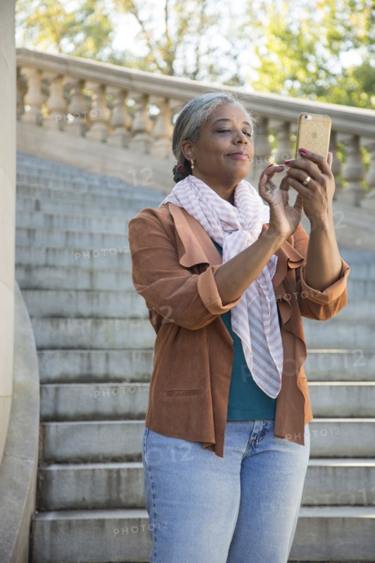 Black woman on stone staircase texting on cell phone