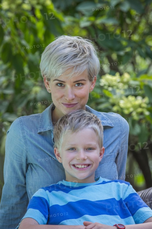 Caucasian boy leaning on mother outdoors