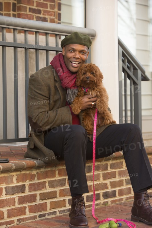 Portrait of African American man sitting on stoop holding dog
