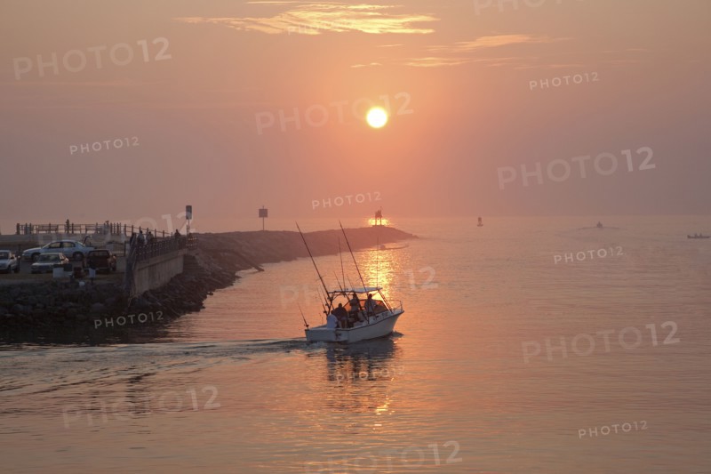 People on boat and at waterfront at sunset