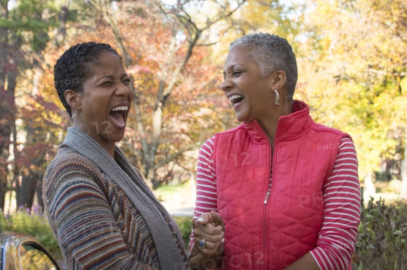African American women holding hands and laughing outdoors