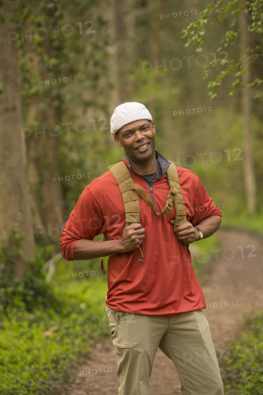 African American man standing on path in forest carrying backpack