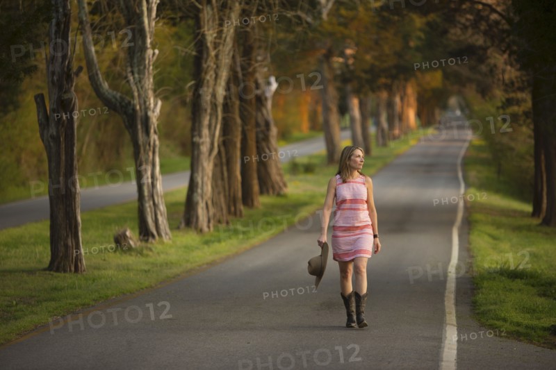 Caucasian woman walking on path holding cowboy hat