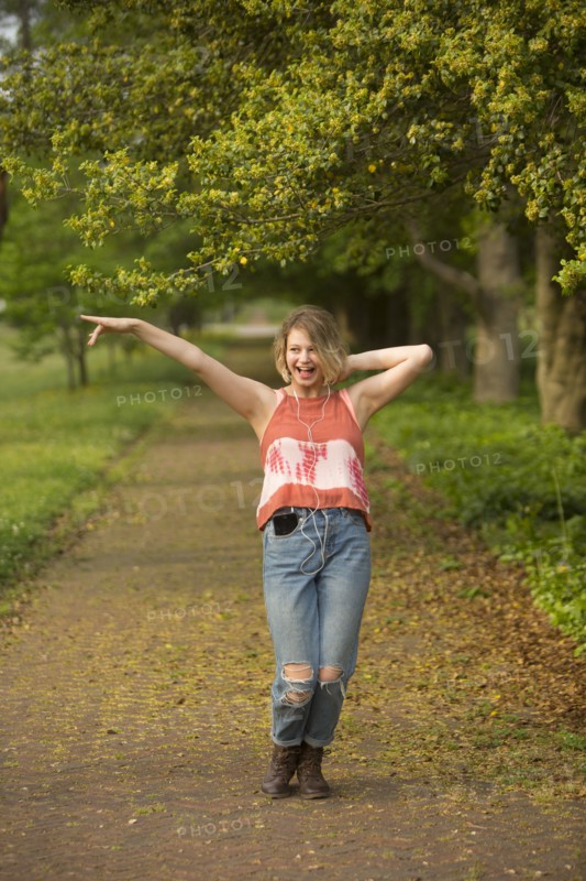 Caucasian girl dancing in park listening to earbuds