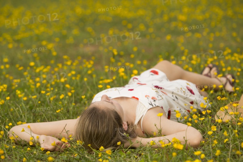 Caucasian teenage girl laying in field of flowers