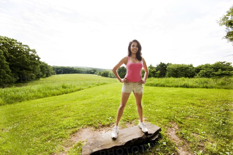 Hispanic woman standing on rock in field