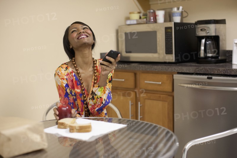 Mixed race businesswoman eating lunch in break room