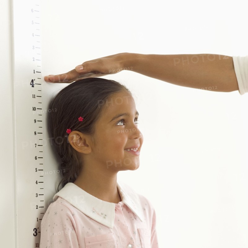 Woman measuring girl's height