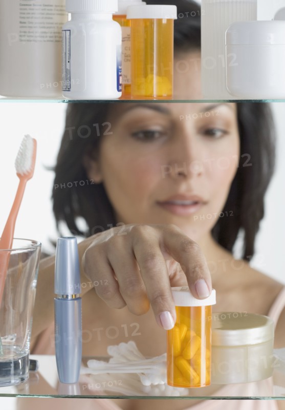 Young woman taking pills out of medicine cabinet