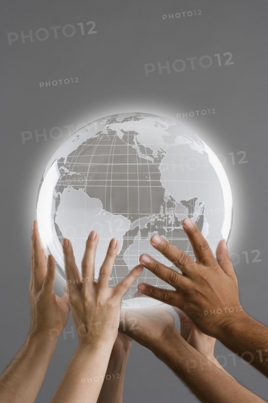 Close up of group of hands holding globe